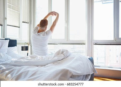 Man stretching in bed, back view