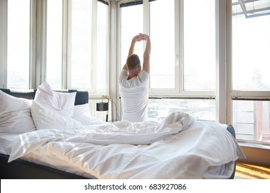 ベッドの背景にストレッチする男性