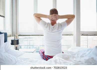 Man stretching in bed, back view