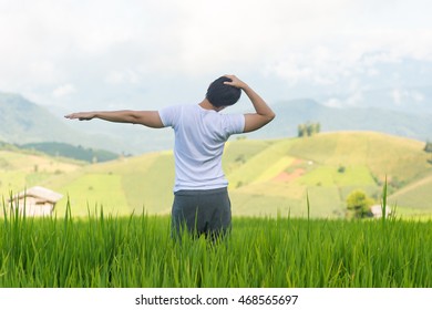 Man Stretching His Neck In Paddy Field With Mountain Background