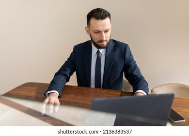 A Man In A Strict Business Suit Works At The Office Walls Behind A Laptop