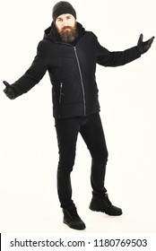 Man With Strict Face Wears Warm Clothes, Isolated On White Background. Winter Clothes Concept. Guy In Black And Brutal Outfit In Motion. Macho With Beard And Mustache Wears Winter Jacket, Gloves, Hat.