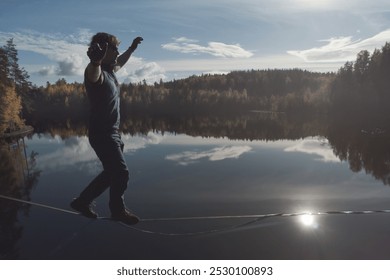 A man strides along a slackline over a mirrored forest lake. Topics of extreme activities - Powered by Shutterstock - Get 15% off with code: PIKWIZARD15
