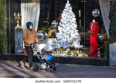 Man With Stroller Walking In The City Near A Shop Or Shopping Center During Covid Or Coronavirus Outbreak, Christmas Background 