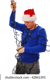 Man struggling with christmas tree lights on white isolated background