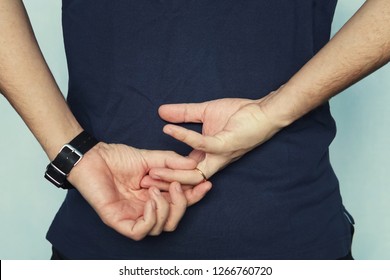 A Man In Struggling To Remove Wedding Ring From His Finger Holding Hands Behind His Back. Concept Of Treason. Husband Cheats On Wife. Cheating Wife