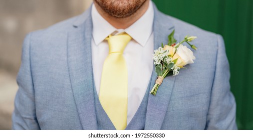 Man With Stubble In A Blue Suit With A White Shirt, Yellow Tie, Vest And Boutonniere, Close-up 