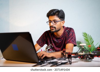 Man or student checking quadcopter or drone by connecting to laptop at laboratory - concept of UAV developing, Repairing or Experimenting.