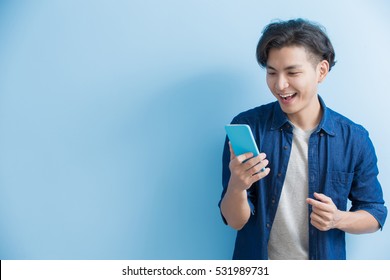 man student smile and use phone isolated on blue background,asian - Powered by Shutterstock