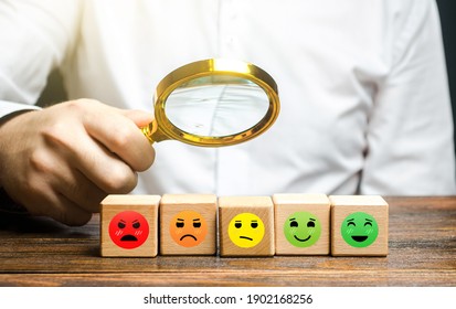 The man studies blocks with mood symbols from happily satisfied to angry unsatisfied. Concept of rating, review. Quality assessment. Communication and feedback. Improving quality of services provided.