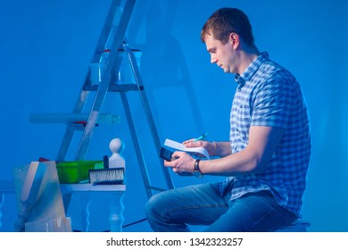 A Man Studies His Expenses. The Cost Of Home Repair. Buying Building Materials. The Builder Calculates The Cost Of Repairs. A Man In A Plaid Shirt.