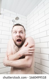 Man with a stupid expression on his face feels shocked at taking a cold shower, he froze and screams, covering his body with hands