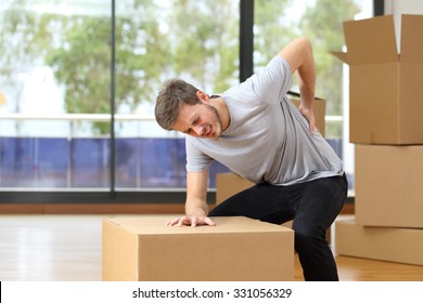 Man suffering back ache moving boxes in his new house