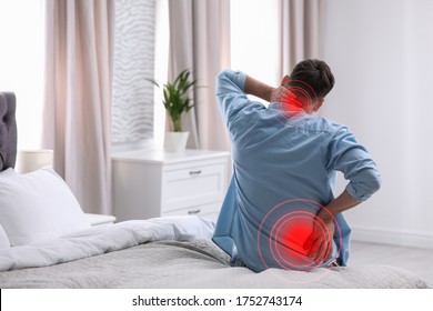 Man Suffering From Back Pain After Sleeping On Uncomfortable Mattress At Home
