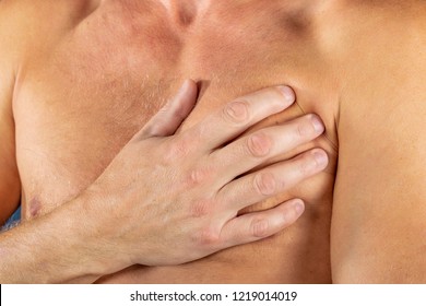 Man suffering from chest pain, having heart attack or painful cramps, pressing on chest with painful expression on blue backgound. Severe heartache