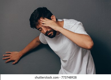 Man Suffering From Dizziness With Difficulty Standing Up While Leaning On Wall