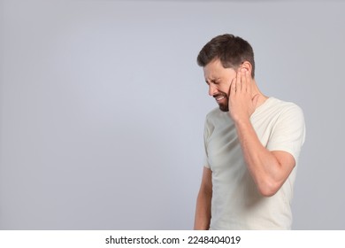 Hombre con dolor de oído en fondo gris