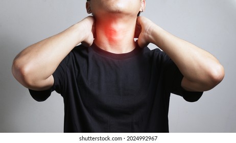 Man suffering he touching inflammated zone on his neck on gray background with health and medical concept.