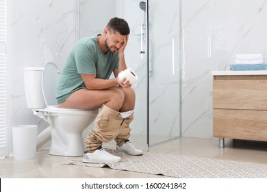 Man suffering from hemorrhoid on toilet bowl in rest room