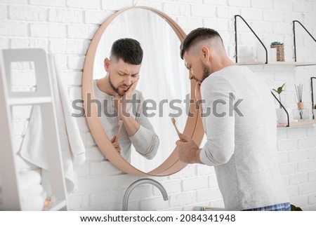Man suffering from pain while brushing teeth in morning