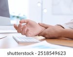 Man suffering from pain in wrist while working on computer at table indoors, closeup. Carpal tunnel syndrome