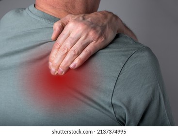 Man suffering from shoulder blade pain. Trigger point. Hand holding shoulder with red point closeup. Back injury. Health care, joint diseases concept. High quality photo