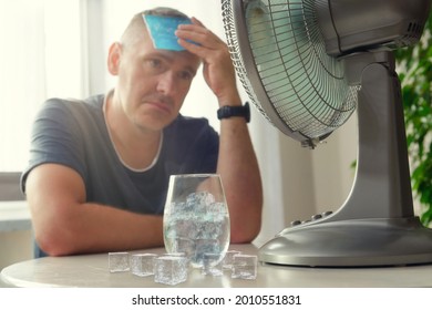 Der Mensch leidet unter Hitze, während er im Zimmer sitzt und versucht, sich durch den Ventilator abzukühlen