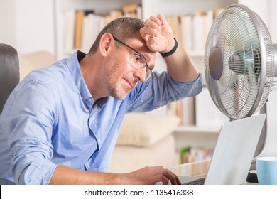 Man Suffers From Heat While Working In The Office And Tries To Cool Off By The Fan