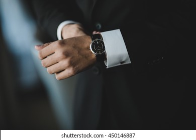 Homem de terno ajusta seu relógio preto no wirst