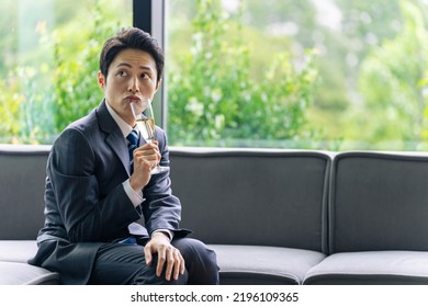 A Man In A Suit Drinking Champagne With An Unimpressed Expression.