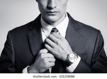 Man In Suit Fixing His Tie. 