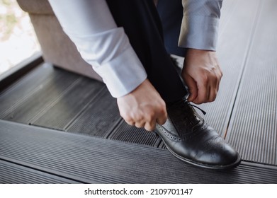 A man in a suit, the groom, close-up puts on shoes, ties his shoelaces - Powered by Shutterstock