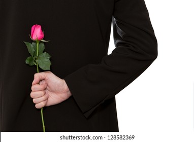 man in suit holding a pink rose in his back - Powered by Shutterstock