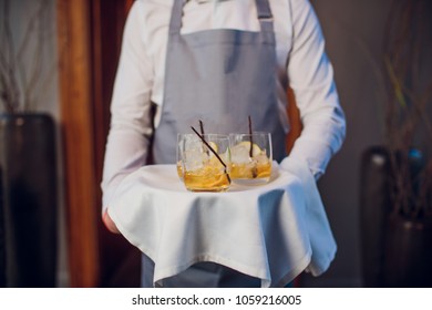 Man in suit holding silver tray with glasses of whiskey