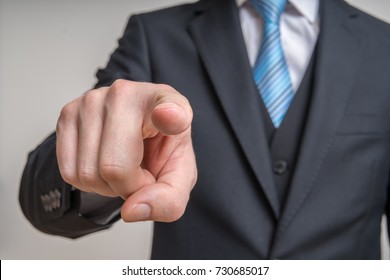 Man In Suit Is Looking At Camera And Pointing Towards You.