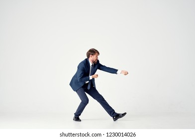 man in a suit on a light background pulls an invisible rope                             - Shutterstock ID 1230014026