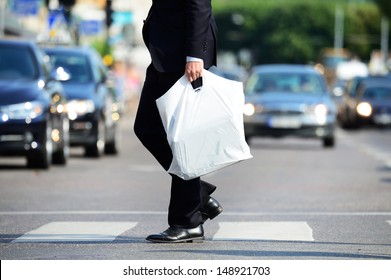 Man In Suit With Plastic Bag Crossing Street