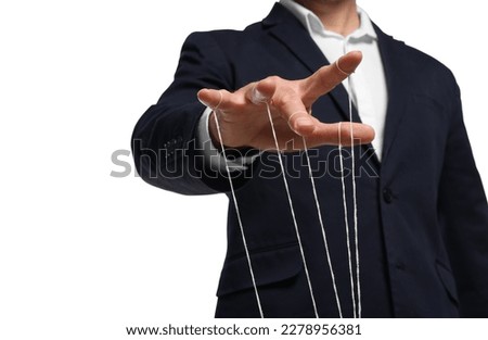 Man in suit pulling strings of puppet on white background, closeup