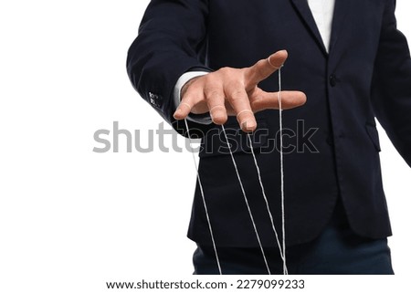 Man in suit pulling strings of puppet on white background, closeup