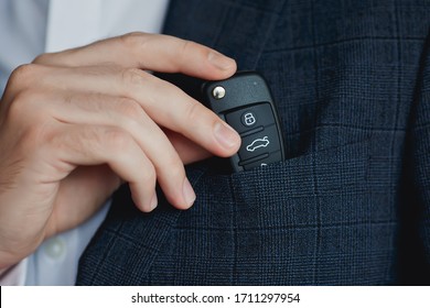 
Man in suit puts car keys in breast pocket.