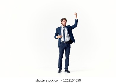 a man in a suit and with a raised hand stands in full growth on an isolated white background                        - Powered by Shutterstock