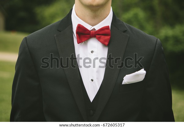 black suit with red bow tie and vest