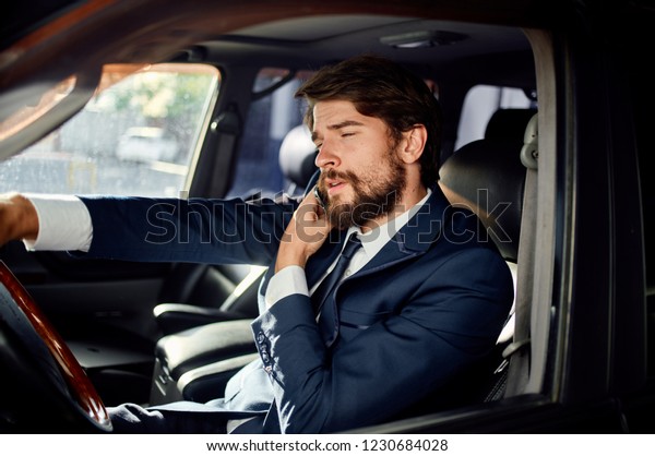 man in a suit sits behind the wheel of a car            \
            