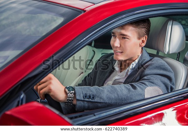 A man in a\
suit sits behind the wheel of a\
car