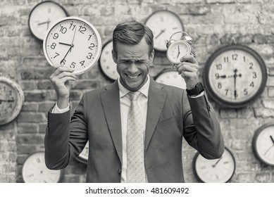 Man in suit standing near wall with clocks