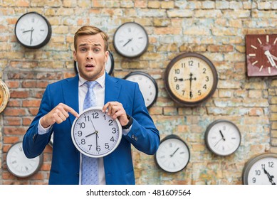 Man in suit standing near wall with clocks