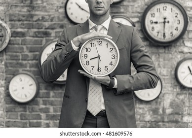 Man in suit standing near wall with clocks
