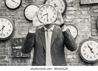 Man in suit standing near wall with clocks