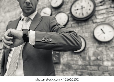 Man in suit standing near wall with clocks