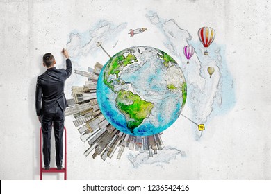 A man in suit standing on a ladder and painting planet Earth with high-rise buildings springing up on it. Development and growth. Building future. Creativity and thriving.